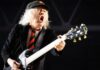 Angus Young verziert ein Baby mit seiner Unterschrift